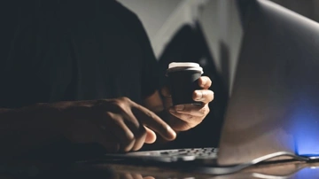 Une personne travaillant efficacement avec un ordinateur portable et une tasse de café.